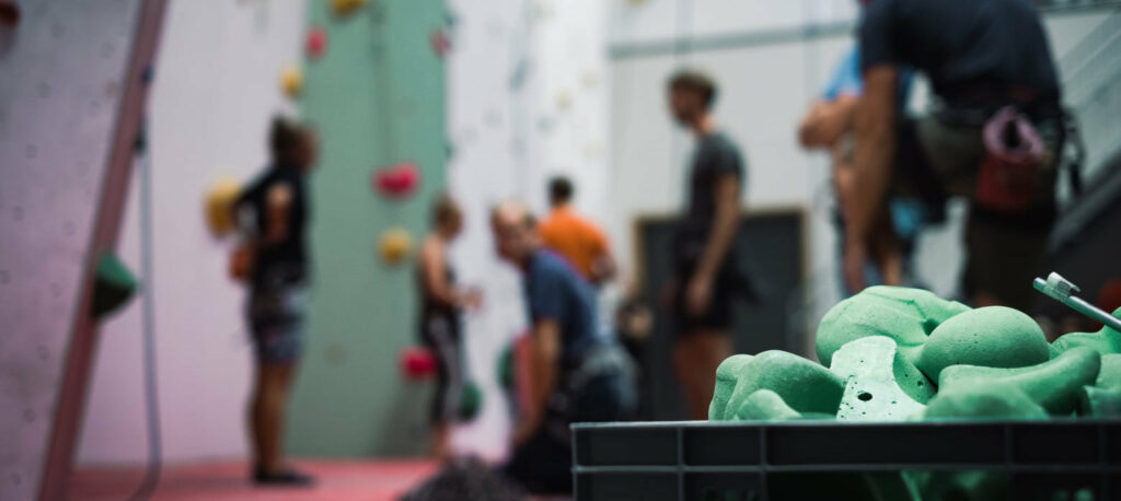 Gröna klättergrepp i förgrunden och klättrare i bakgrunden